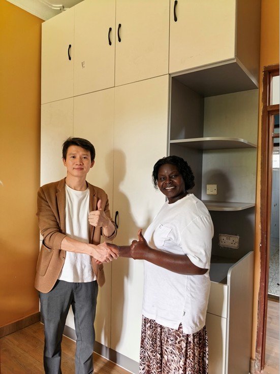 Satisfied client with Uganda Doors Interior team celebrating completed custom wardrobe installation in Uganda home