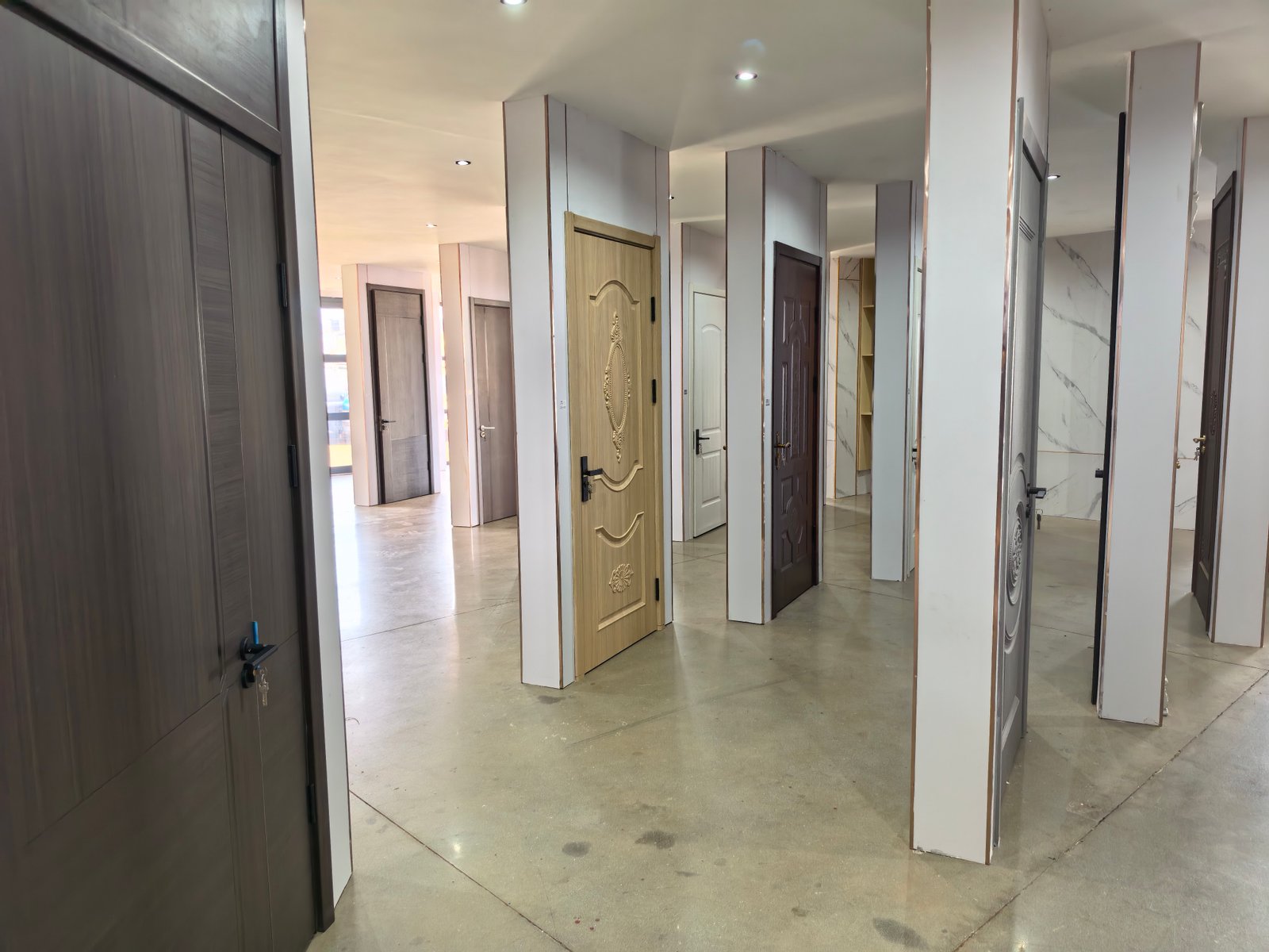 Multiple door samples and styles displayed on showroom wall at Uganda Doors Interior Kampala